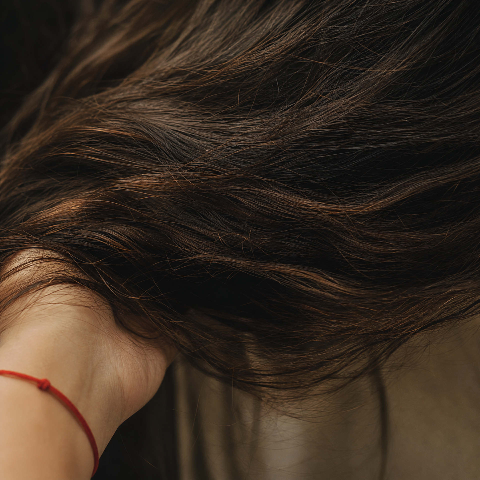 手で形づくられる、深いブラウンのウェーブヘアの質感